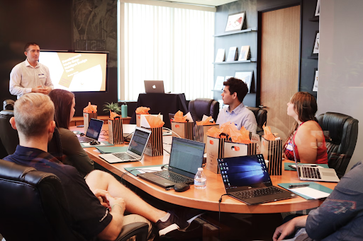 Office staff in a board room with a speaker presenting alongside a big screen